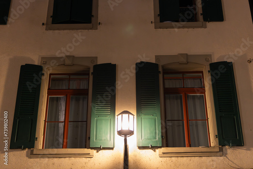 windows in the building with a gaslamp lighning up the street