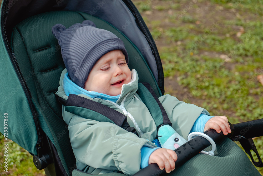 crying child in stroller in spring park