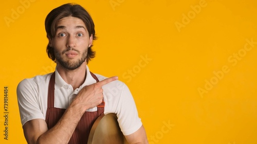 Astonished Man Wearing Apron Pointing Aside With Fingers Isolated Young Waiter Looking Amazed Showing Copy Space Yellow Background