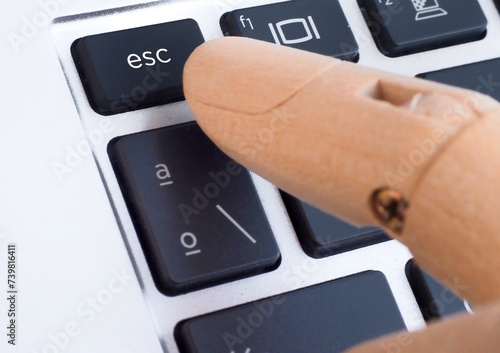 Wooden finger pressing esc button on computer keyboard photo