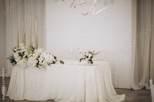 Wedding celebration hall with wedding arch decorated with flowers and white fabric