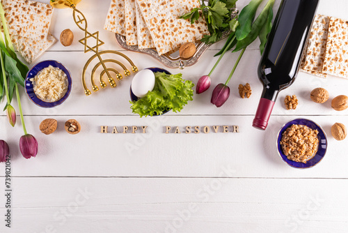 Festive background for the spring holiday of the Jewish Passover. Traditional foods, flowers, minor candlestick. Text of Happy Passover. photo