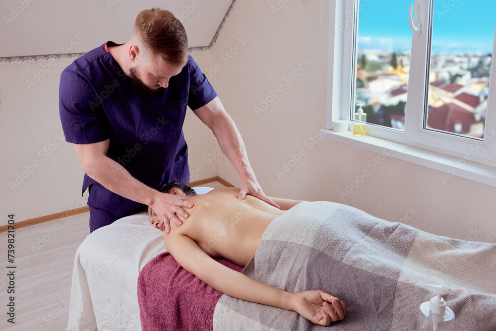 Obraz premium Young masseur gives back massage to woman in her 20s.