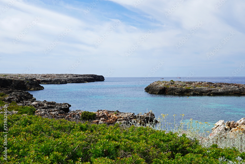 Natural landscape of Playa de Cavalleria (Mercadal) in Minorca beach with clear blue sky and rocky seashore- Menorca, Spain