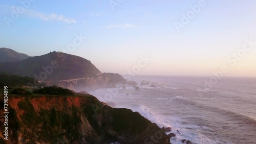 Bixby Creek Bridge Big Sur California aerial cinematic drone flight Pacific Ocean Nor Cal winter summer big wave swell crashing rugged coastline afternoon golden hour pink sunset backward motion