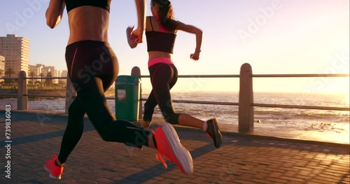 Friends, running and sunset in beach, exercise and fitness for wellness, cardio and training in city. Runners, workout and speed in promenade, young and sprint for health, sport and race together photo