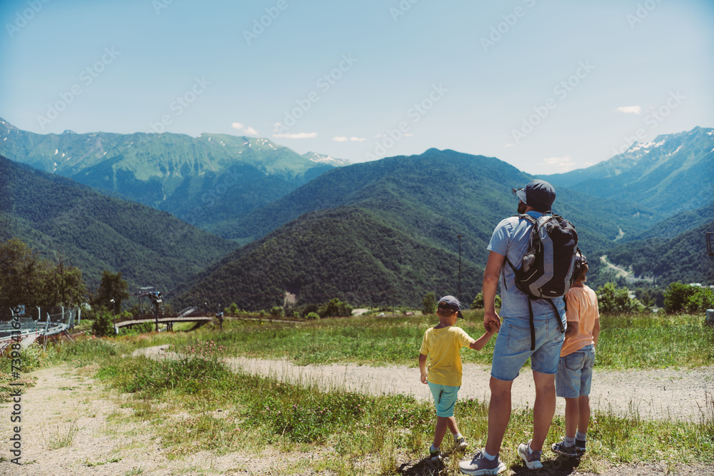 Fototapeta premium Travel hiking with children. Man with sons enjoying beautiful view of Caucasus Mountains 