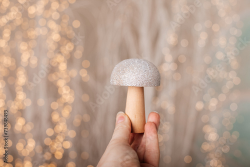 Wooden mushroom figurine in hand with blurred lights.