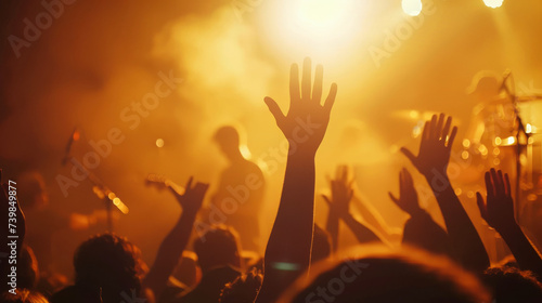 Back view of crowd at a big concert or event, with hands up