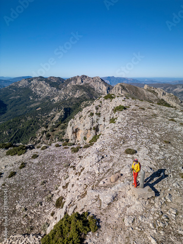 A woman standing on a rocky point overlooking Mediterranean sea, Malla del Llop peak, Alicante, Costa Blanca, Spain - stock photo photo