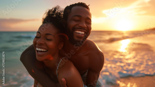 Portrait of an African American couple having fun on the beach near the ocean at sunset. Black couple laughs and hugs on vacation, on their honeymoon. Time together concept. Active lifestyle.