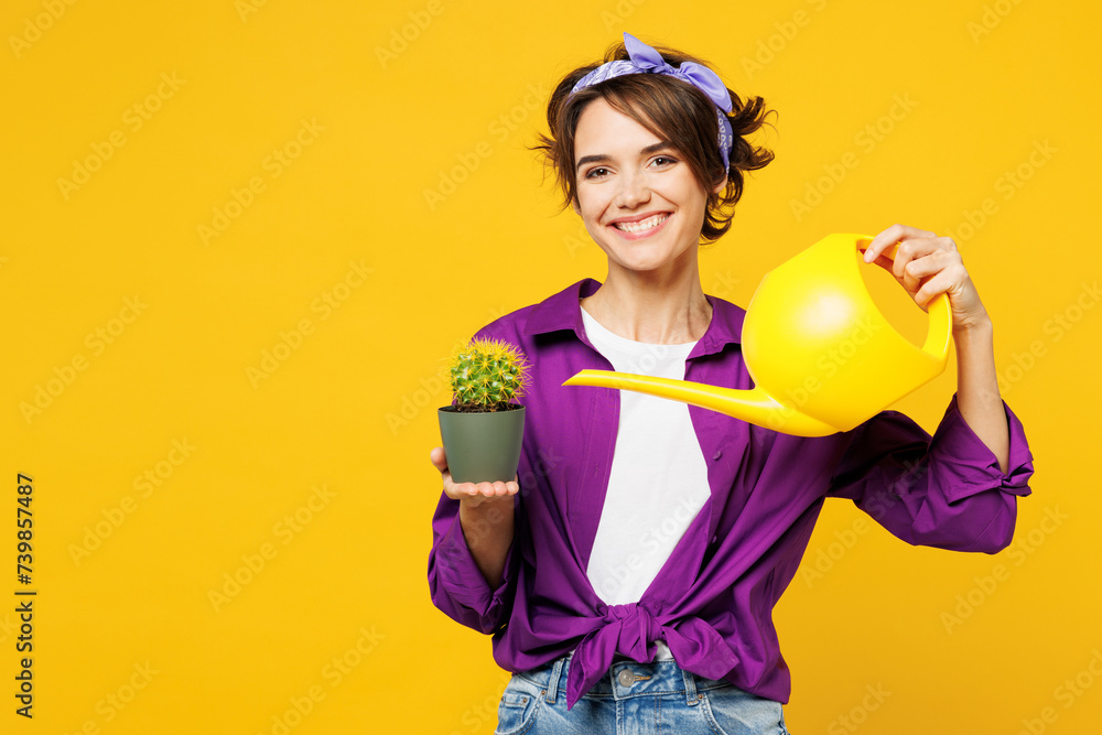 Young smiling happy cheerful woman she wear purple shirt rubber gloves casual clothes do housework tidy up water cactus plant isolated on plain yellow background studio portrait. Housekeeping concept. - obrazy, fototapety, plakaty 