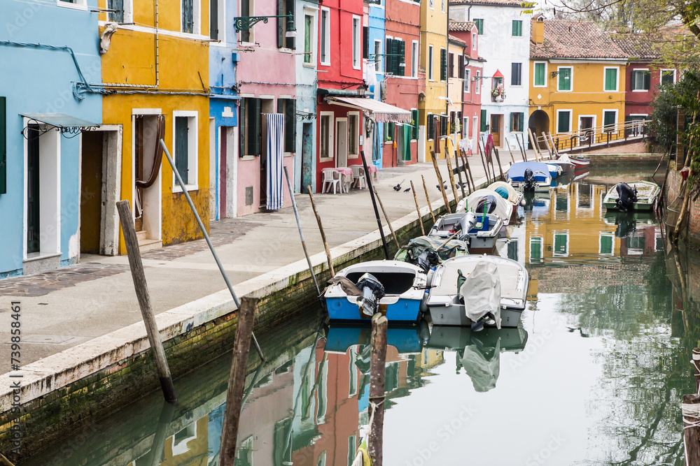Murano and Burano island landscape. Venice region in Italy. Colorful carious home facades. Water in canal. Parked boats.