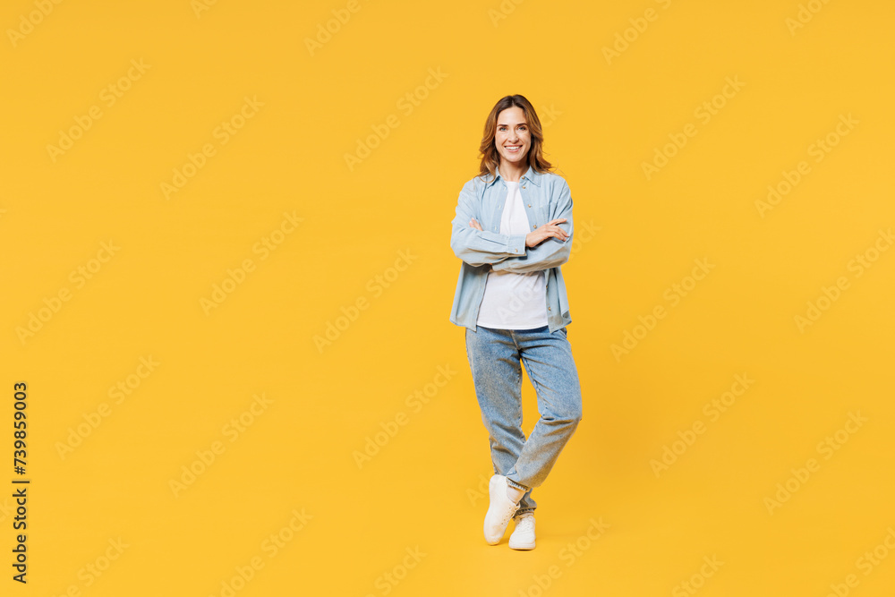 Full body smiling happy cool young woman she wear blue shirt white t-shirt casual clothes hold hands crossed folded look camera isolated on plain yellow background studio portrait. Lifestyle concept. Full body smiling happy cool young woman she wear blue shirt white t-shirt casual clothes hold hands crossed folded look camera isolated on plain yellow background studio portrait. Lifestyle concept.