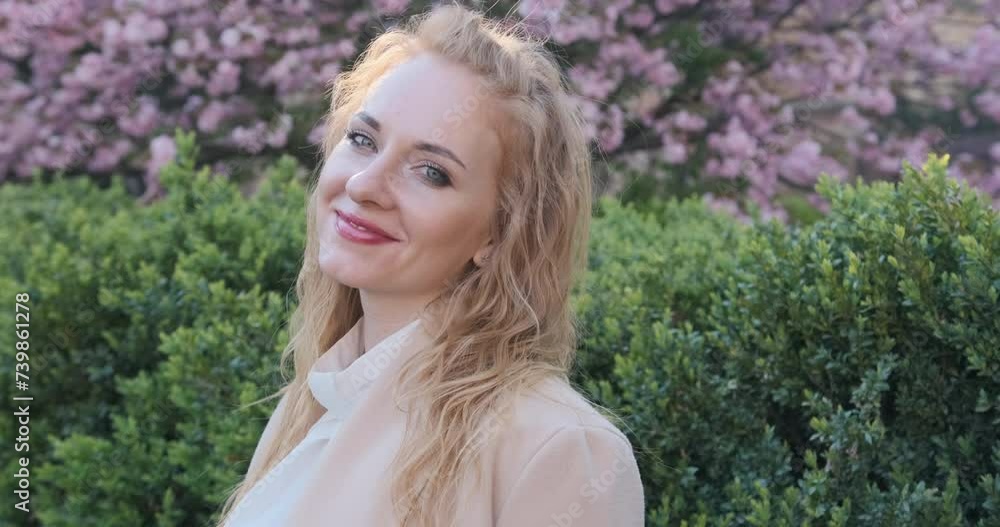 Portrait of a beautiful woman with long blond hair in a park with cherry blossoms Portrait of a beautiful woman with long blond hair in a park with cherry blossoms