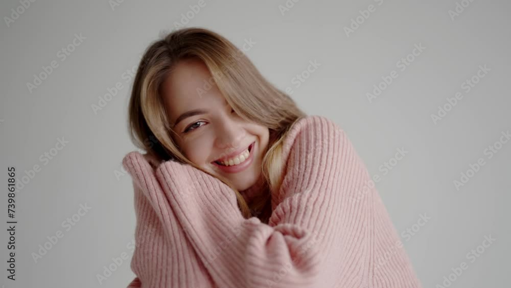 Young beautiful woman in pink knitted sweater smile and looking at camera in studio with white background. Portrait of cheerful pretty female Young beautiful woman in pink knitted sweater smile and looking at camera in studio with white background. Portrait of cheerful pretty female
