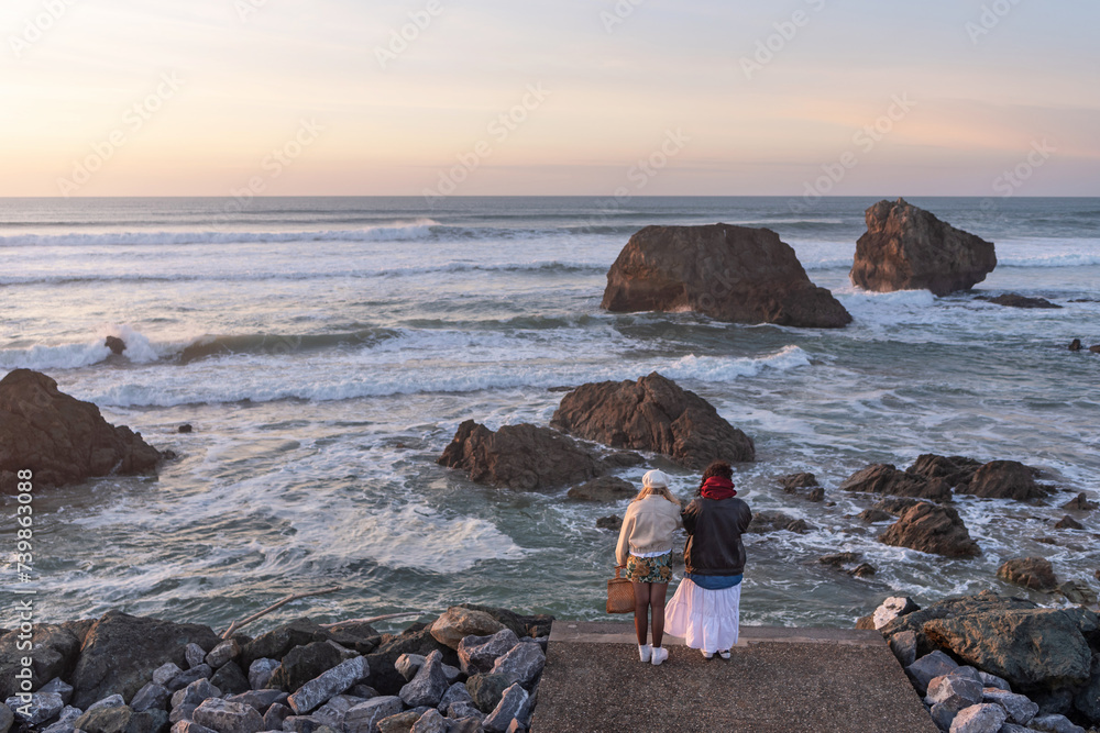 Two women taking photos at sunset in the sea. French Basque Country