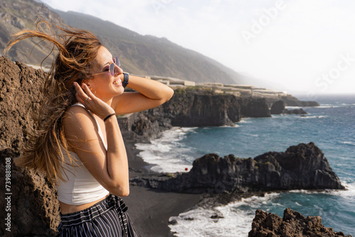 woman smiling facing the sun and the wind at a beach viewpoint