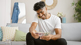 A cheerful young hispanic man counts polish zloty cash at home.
