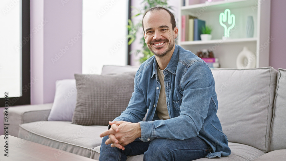 Smiling bald man sitting on sofa in a modern living room