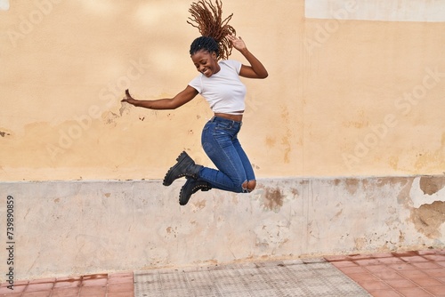 African american woman smiling confident jumping at street