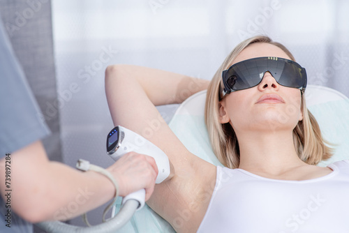 Professional beautician removes hair on armpit using a laser. Armpit hair removal with laser,  procedure at clinic photo