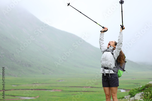 Excited hiker raising poles celebrating vacation