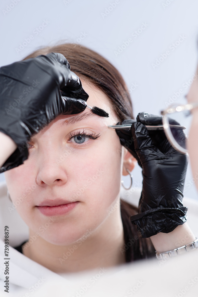 Young woman undergoing eyebrow correction procedure in beauty salon Young woman undergoing eyebrow correction procedure in beauty salon