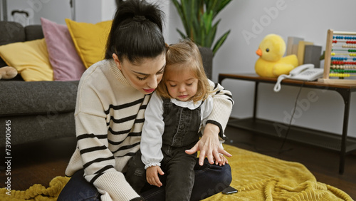 Woman and girl, presumable mother and daughter, share a heartwarming moment on a cozy room floor surrounded by toys. photo