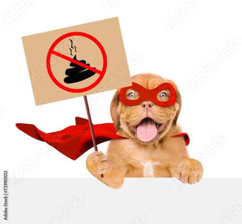 Funny Mastiff puppy wearing superhero costume holds sign "no dog poop" above empty white banner. Concept cleaning up dog droppings. Isolated on white background