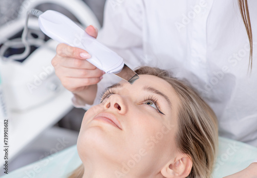 Beautiful woman receiving ultrasound cavitation facial peeling at spa salon. Cosmetology and facial skin care. Profissional facial treatment and face cleansing