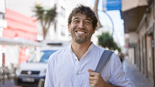 Handsome hispanic man with beard smiling in urban street setting photo