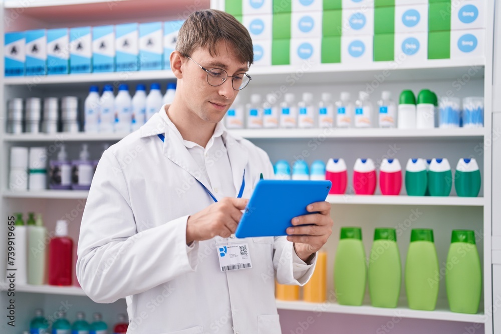 Young caucasian man pharmacist using touchpad working at pharmacy Young caucasian man pharmacist using touchpad working at pharmacy