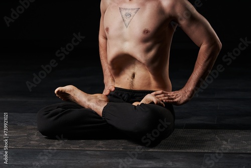 Poised in lotus meditation, stomach vacuum in motion, the man's all-seeing eye tattoo represents inner enlightenment.