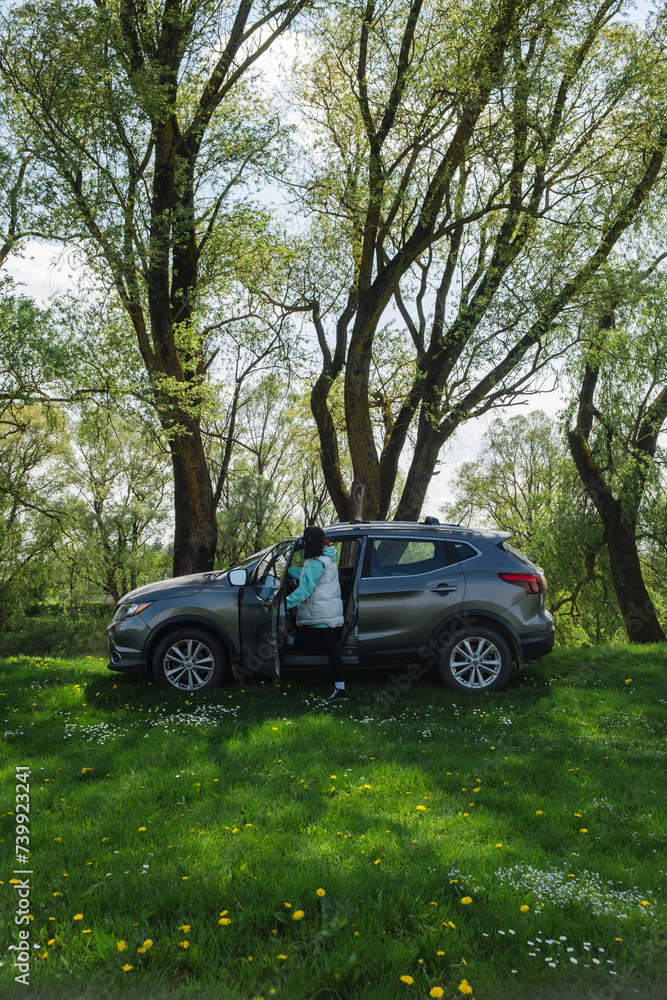 a woman gets into a parked car on a green lawn in nature