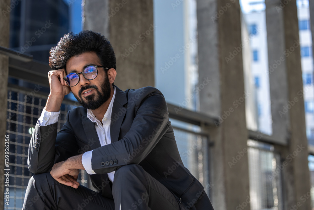 Young hindu businessman sitting on steps and looking tired and stressed Young hindu businessman sitting on steps and looking tired and stressed