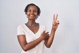 African woman with dreadlocks standing over white background smiling with happy face winking at the camera doing victory sign. number two.