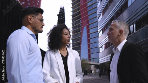 Multiracial business people talking outside corporative buildings, discussing about new projects together. photo