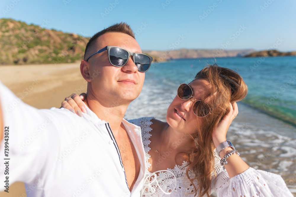 Young happy couple taking selfie on the beach. Summer vacations concept. Young happy couple taking selfie on the beach. Summer vacations concept.