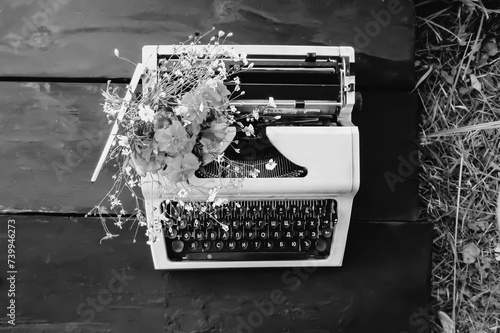Obraz na plátně Vintage typewriter machine and summer flowers outdoors.