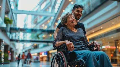 femme handicapée dans un fauteuil roulant dans le hall d'un grand centre commercial avec un ami valide qui l'aide photo