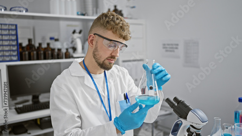 Caucasian man examines chemical in flask at laboratory, showcasing research