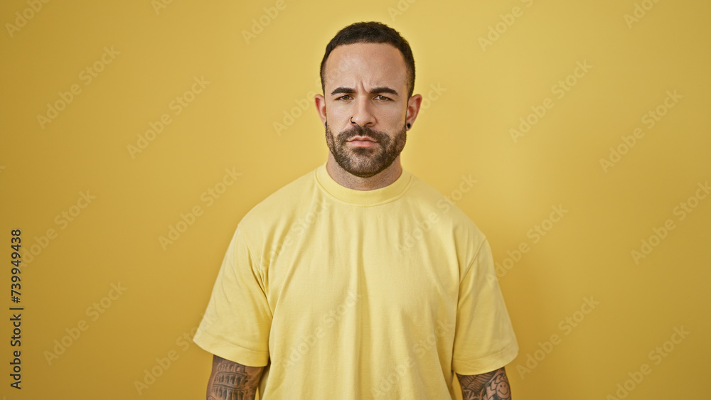 Portrait of a handsome hispanic man with a beard, standing against a yellow isolated background. Portrait of a handsome hispanic man with a beard, standing against a yellow isolated background.
