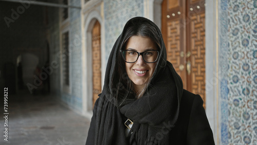 Smiling woman with glasses in topkapi palace, istanbul, showcasing multicultural tourism and architecture. photo