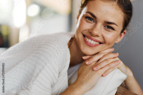 Woman resting on a cozy couch at home, wearing a comfortable sweater and looking joyful Her natural beauty shines through her smiling face as she relaxes in the warm and inviting living room She is photo