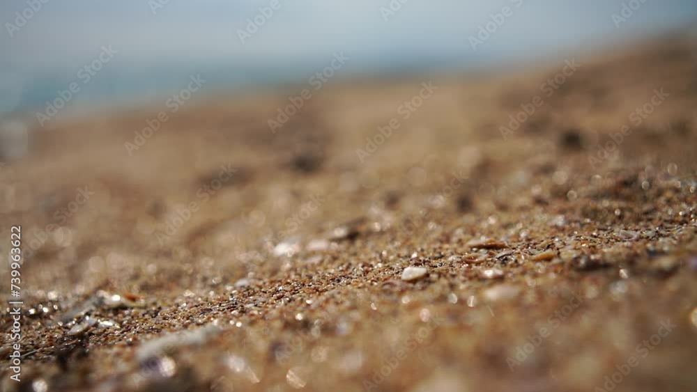 Sand flows in slow motion against the bokeh background of the beach and sea. Sand flows in slow motion against the bokeh background of the beach and sea.