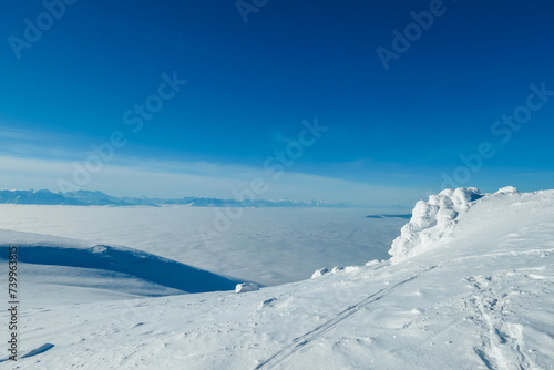 Scenic view of fog covered Lavanttal valley surrounded by snow capped mountain peaks Karawanks and Julian Alps seen from top of Grosser Speikkogel, Kor Alps, Lavanttal Alps, Carinthia Styria, Austria © Chris