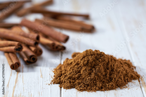 cinnamon sticks and cinnamon powder on a white wooden table, selective focus.