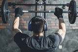 athlete with headphones and gym gloves lifting barbell