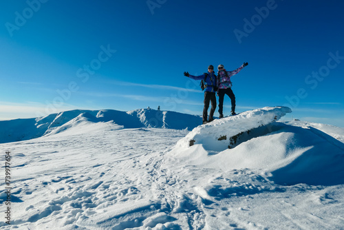 Couple in snowshoes on snow covered mountains of Kor Alps, Lavanttal Alps, Carinthia Styria, Austria. Winter wonderland in Austrian Alps. Snow shoe tourism. Looking at summit peak Grosser Speikogel